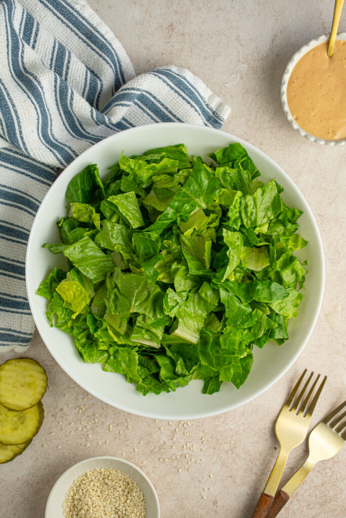 A white salad bowl filled with chopped romaine lettuce.