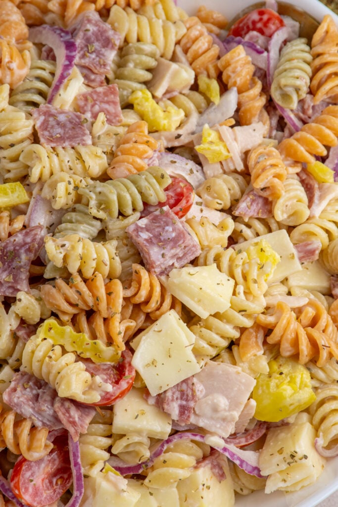 Close up of colorful grinder pasta salad with pasta, deli meats, cheeses, and veggies.