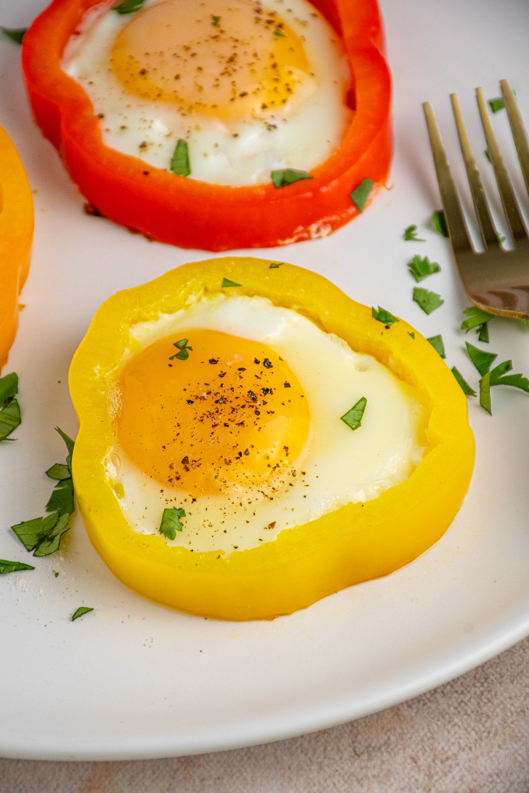 A yellow pepper ring filled with a cooked egg and garnished with salt and pepper.