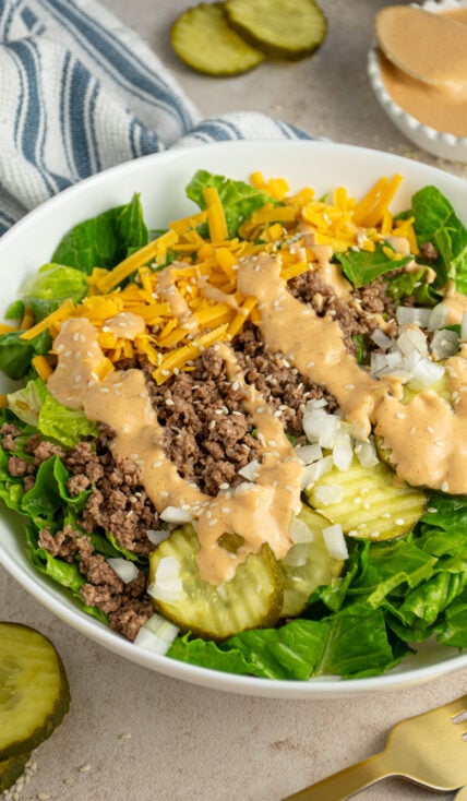 A white bowl with big mac salad with ground beef, cheese, pickles, and big mac sauce.