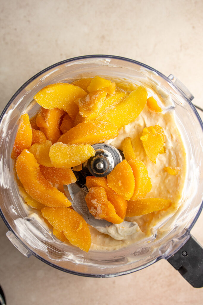 Adding frozen peaches to the smooth peach yogurt filling for popsicles.