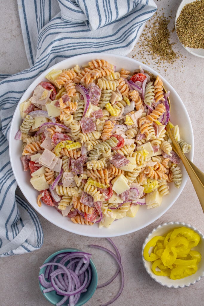 Overhead view of a white bowl with colorful italian grinder pasta salad filled with deli meats, cheeses, and veggies.