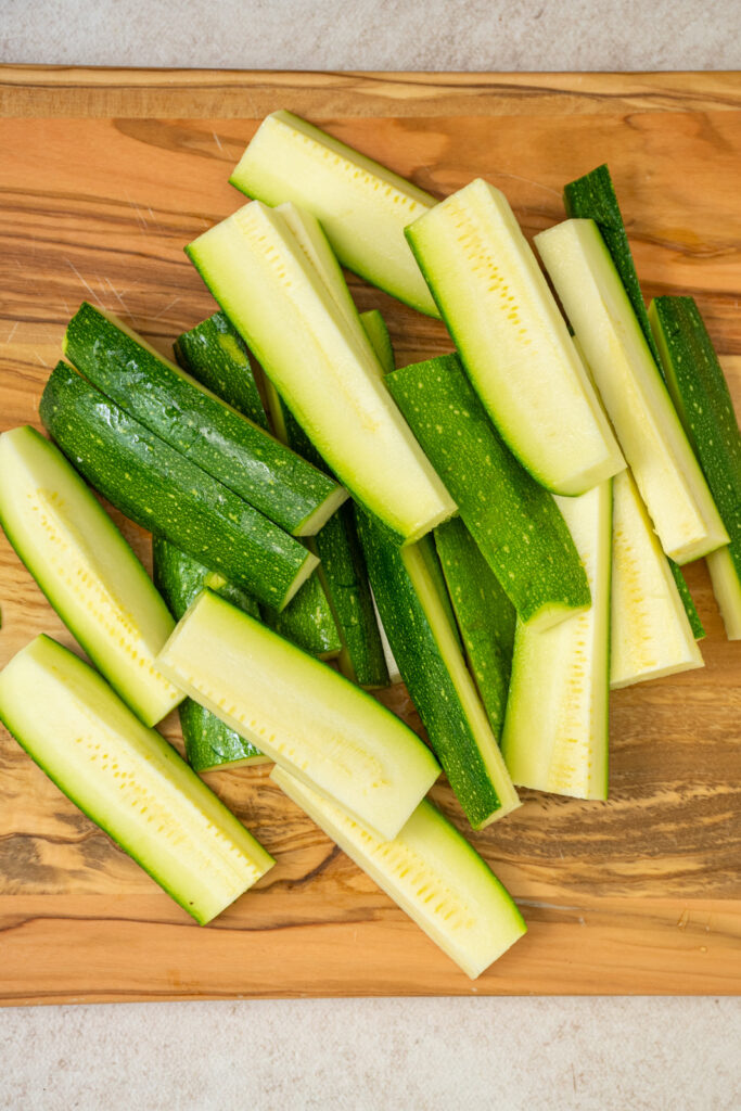 Cut zucchini on a wooden cutting board.