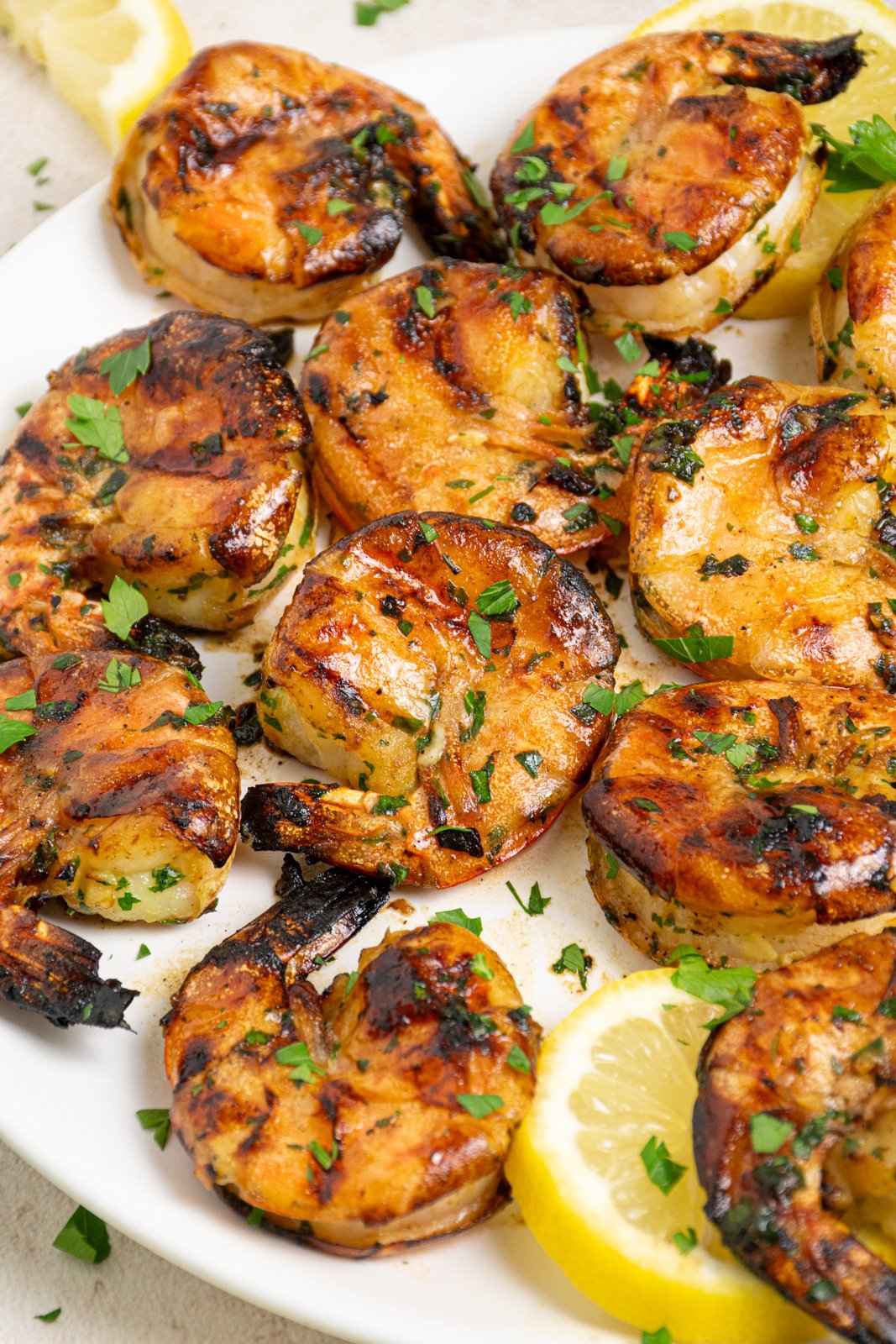 White plate filled with grilled jumbo shrimp garnished with fresh parsley.