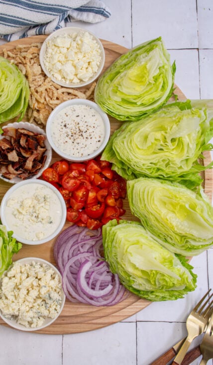 A large wood board filled with the toppings for making a wedge salad board.