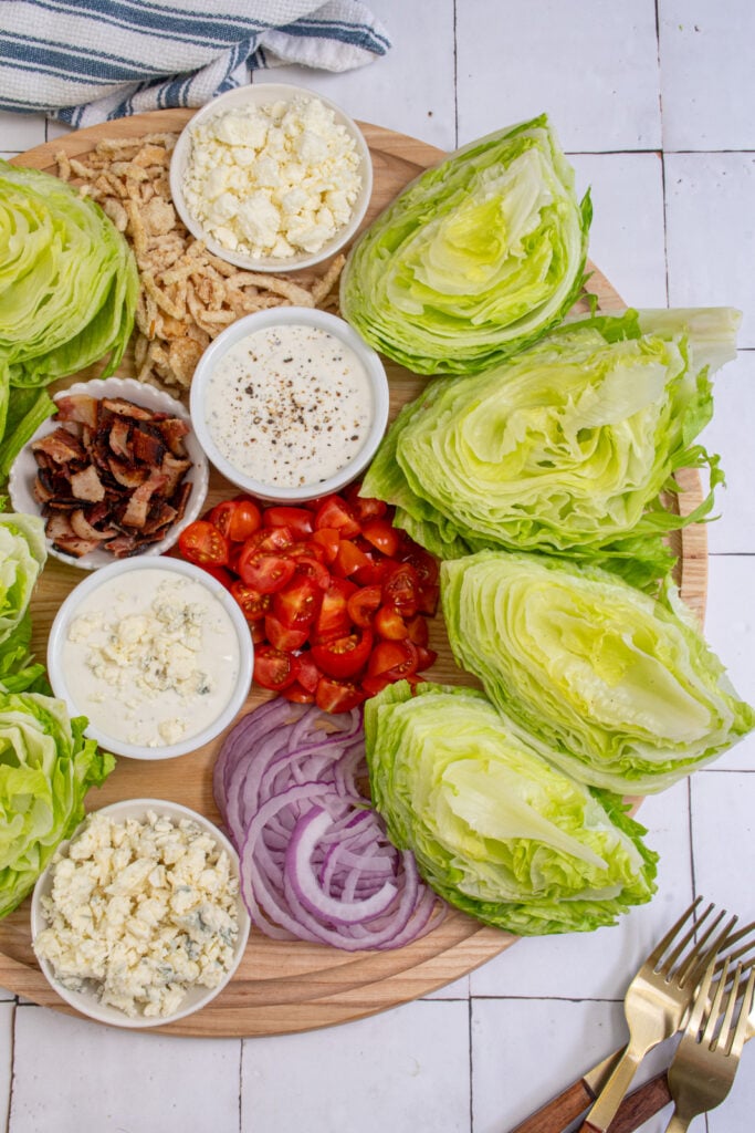 A large wood board filled with the toppings for making a wedge salad board.