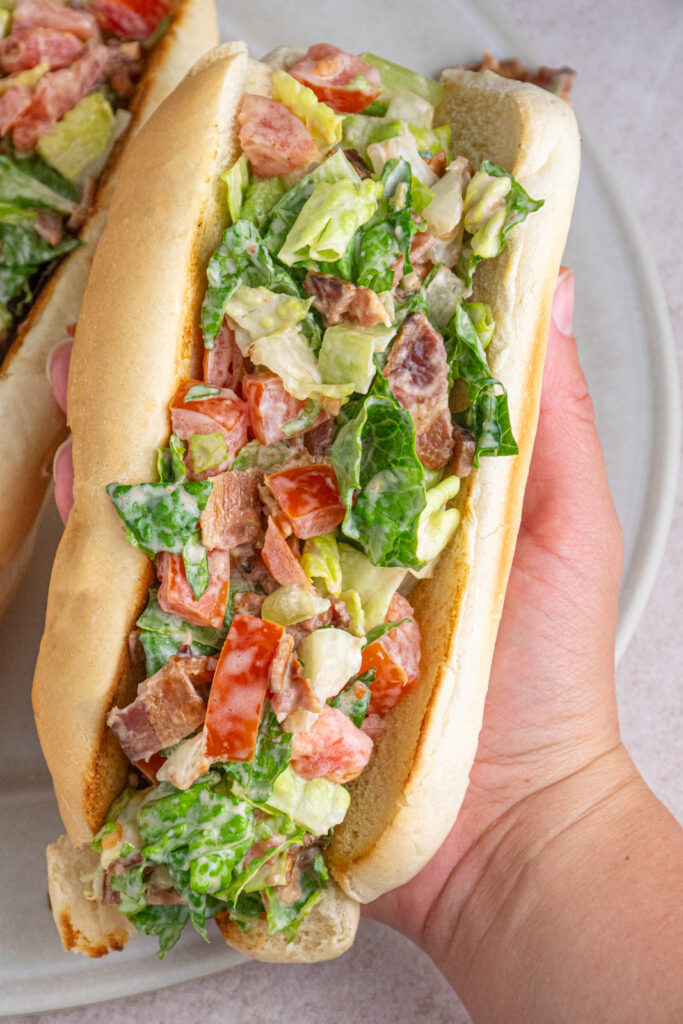 A hand holding a chopped BLT sandwich.
