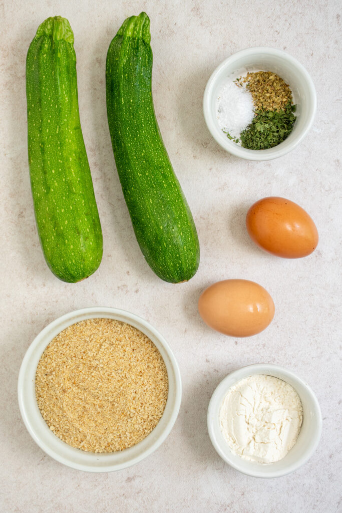 Ingredients needed to make baked zucchini fries all laid out on a tabletop.