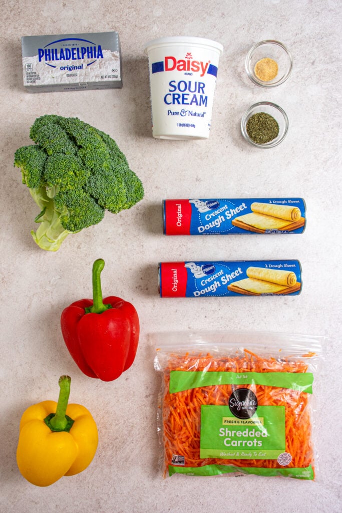Ingredients needed to make crescent roll veggie pizza laid out on a table top.