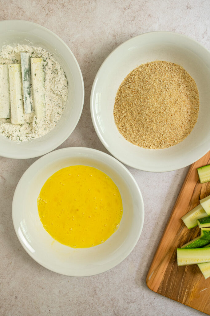 Dipping the zucchini in the flour mixture.