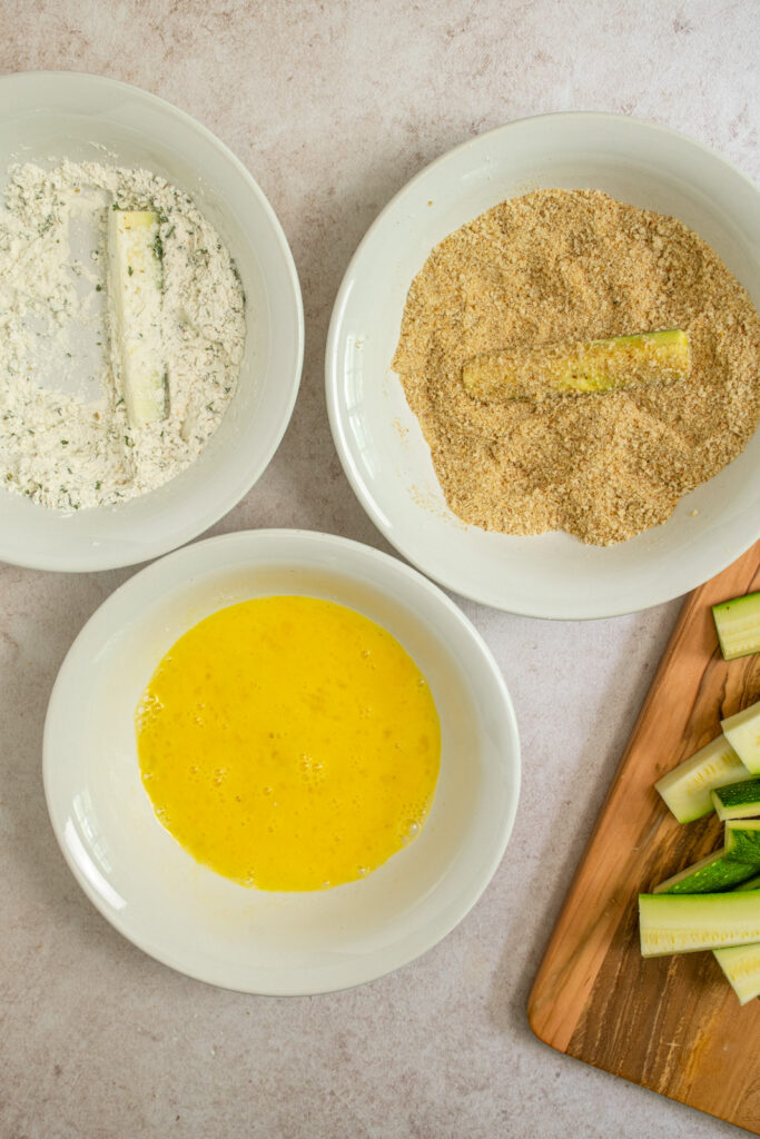 Adding breadcrumbs to a zucchini fry.