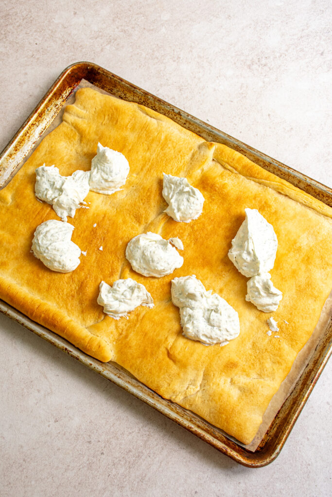 Dabs of dill dip on the golden brown crescent sheet.
