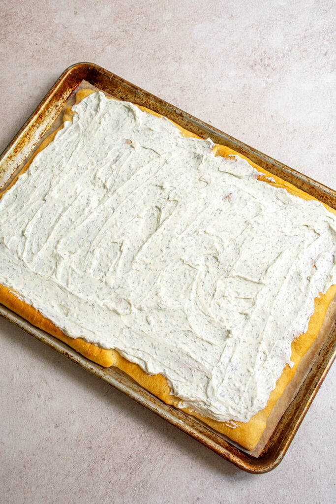 The dill dip topping spread overtop the base of the veggie pizza.
