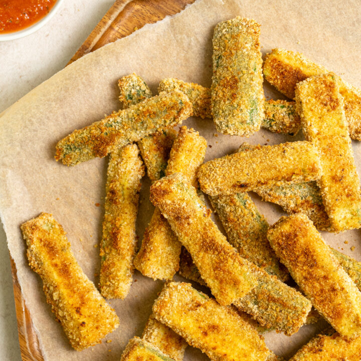A tray of crispy baked zucchini fries sitting next to a side of marinara sauce.