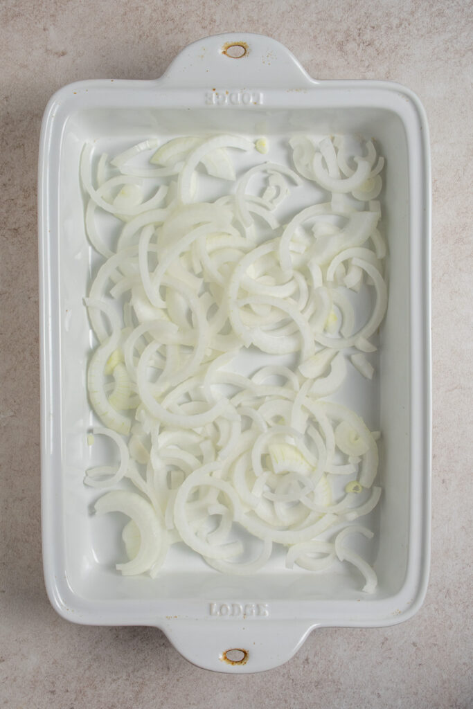 Adding sliced onions to a casserole dish.