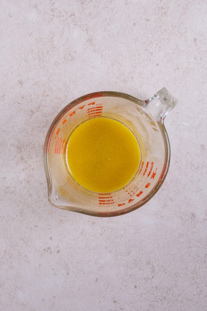 The dressing for sugar snap pea salad in a glass measuring cup.