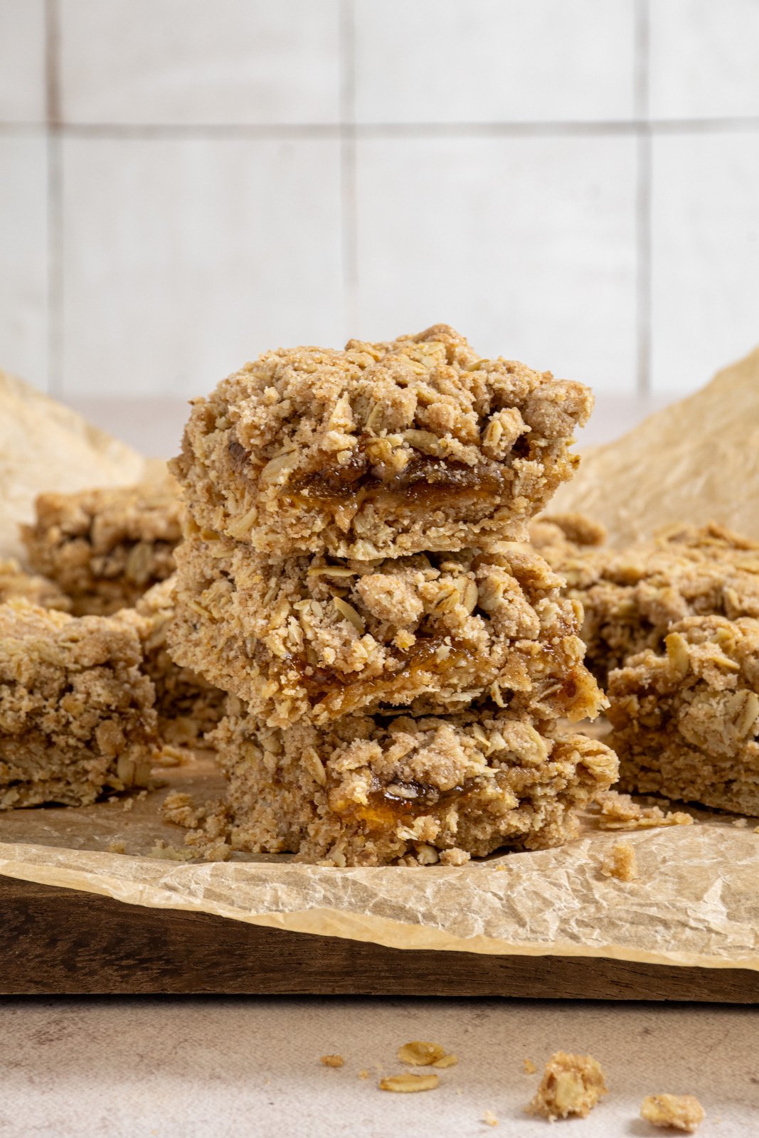 A stack of three fig oat bars showing of the chewy oatmeal crust and crumble topping with fig jam in the middle.