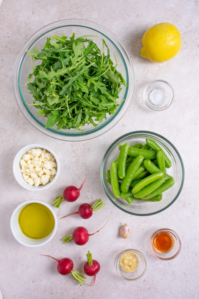 Ingredients for making sugar snap pea salad laid out on a table top.