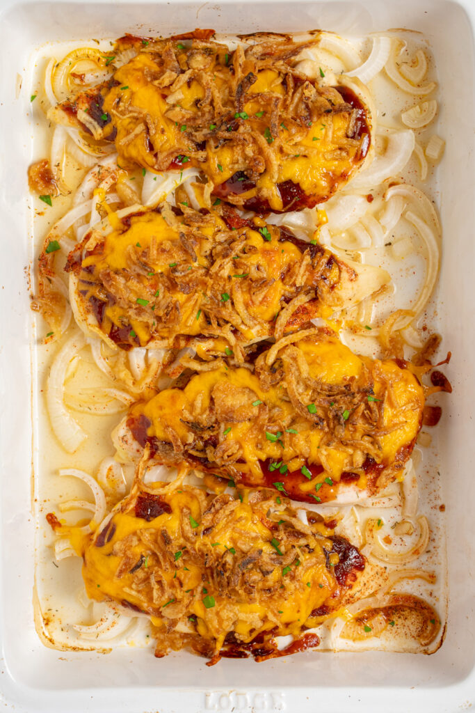 Oven baked cheesy bbq chicken breasts in a white casserole dish.