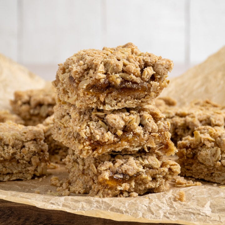 A stack of homemade fig oat bars on a piece of brown parchment paper.