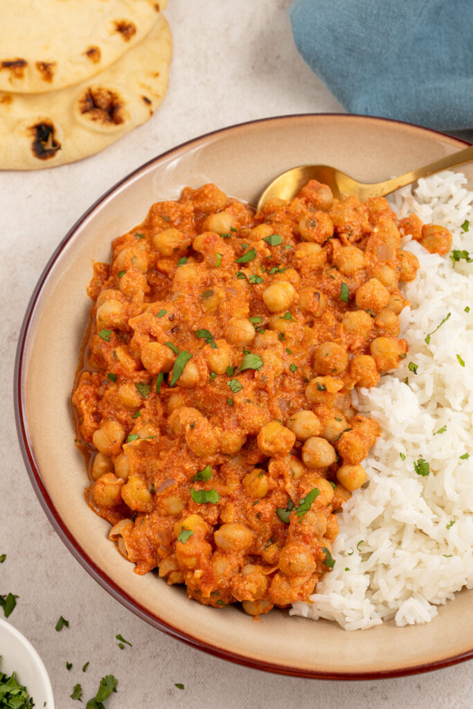 A bowl with a serving of chickpea tikka masala with a bed of rice.