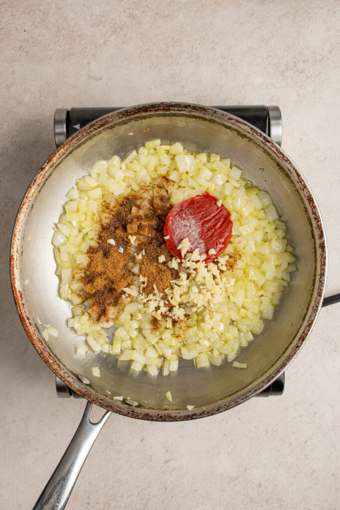 Making the sauce for chickpea tikka masala by adding the spices to the softened onions.