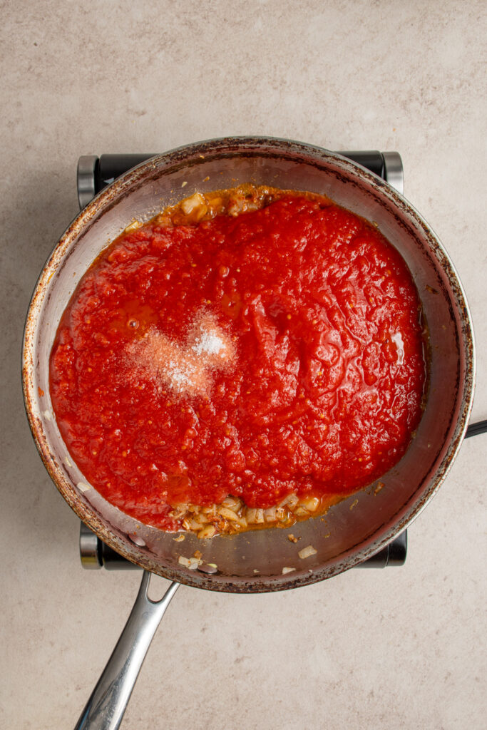 Adding kitchen ready tomatoes and salt to the the onions and spices.