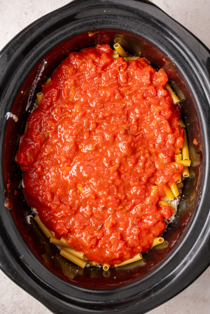 A layer of tomato sauce overtop noodles for baked ziti.
