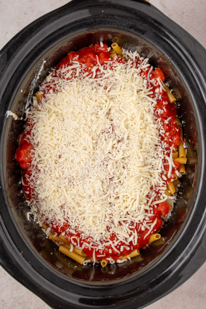 Shredded cheese added as the last layer on top of the crockpot ziti.