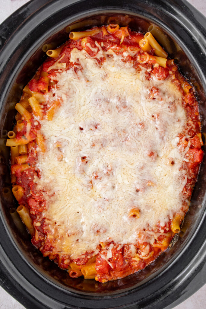 Freshly cooked crockpot ziti with melted cheese on top.