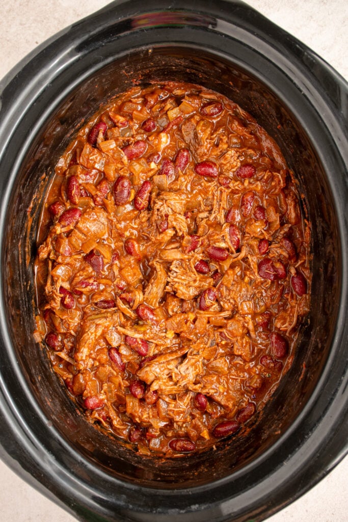 Easy to make chuck roast chili in a black crockpot with shredded beef and beans.