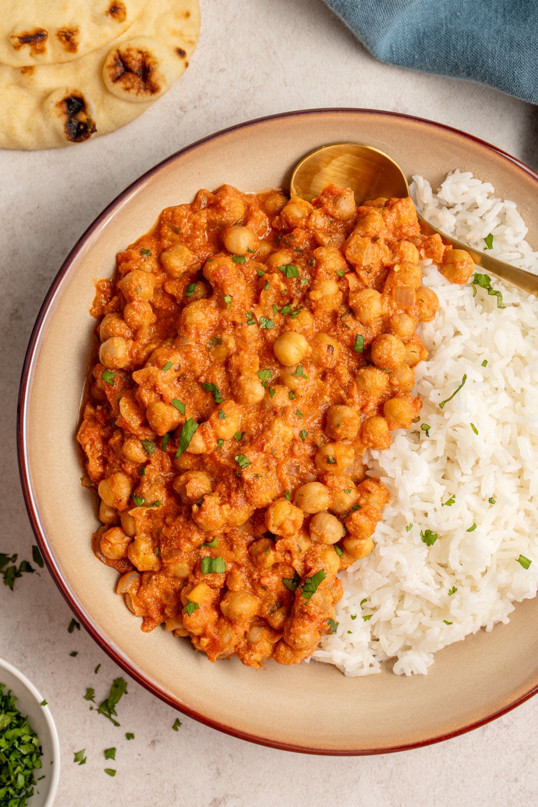 A bowl filled with half rice and half chickpea tikka masala made in the slow cooker garnished with fresh cilantro.