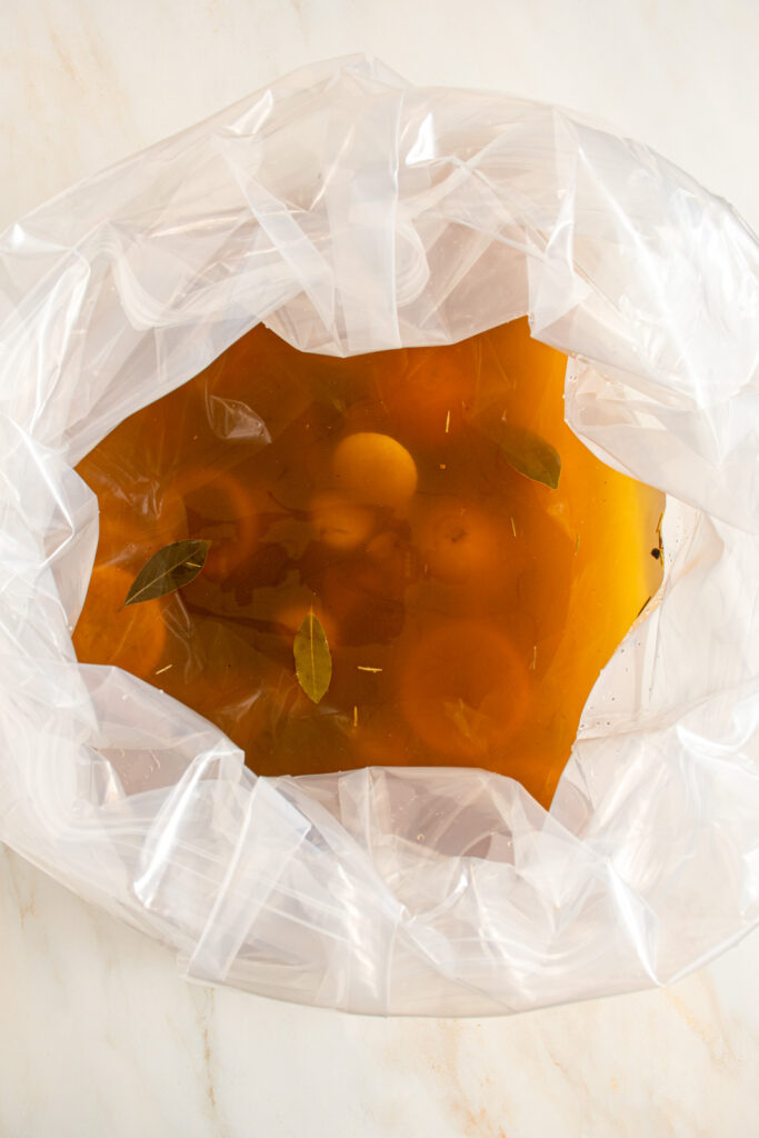 Apple cider turkey brine in a large brining bag with slices of lemons and oranges, bay leaves, garlic, and spices.