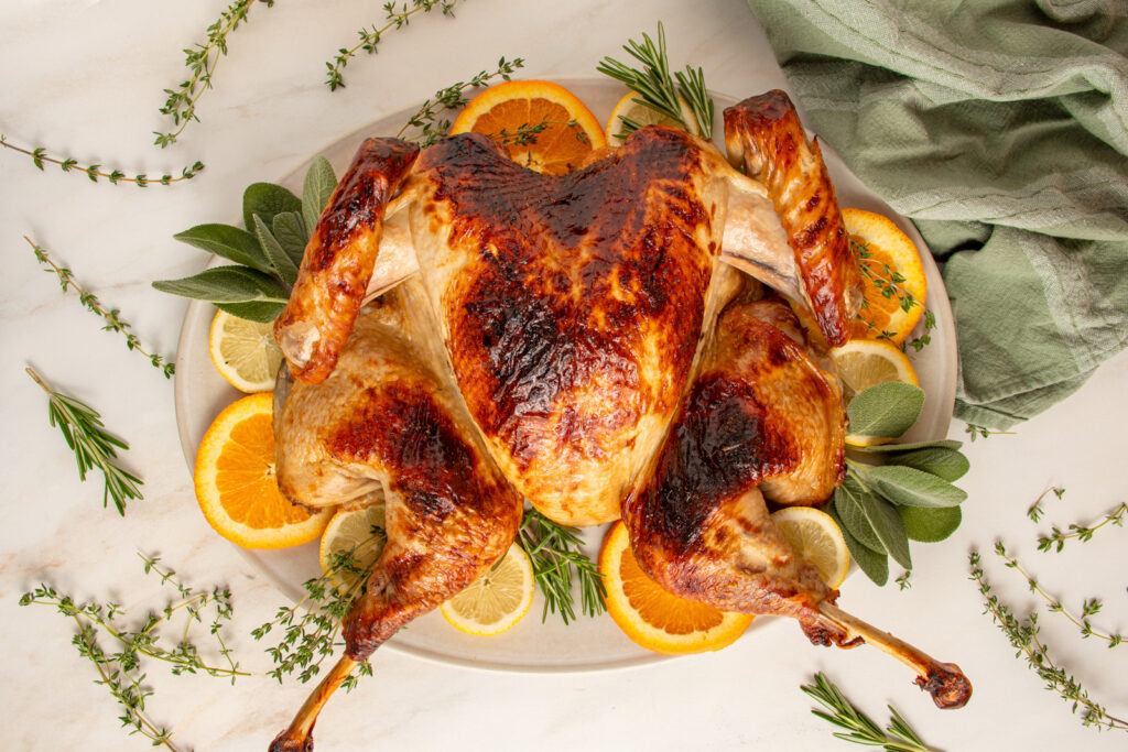 A juicy roast spatchcock turkey on serving platter with fresh herbs.