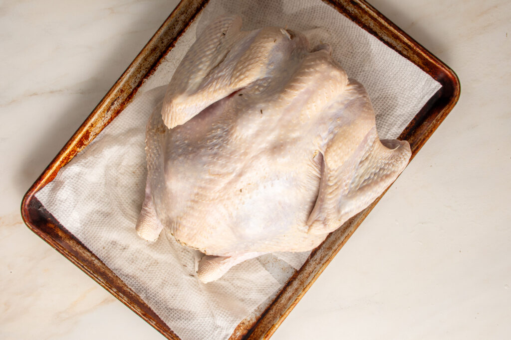 A raw turkey on a sheet pan.