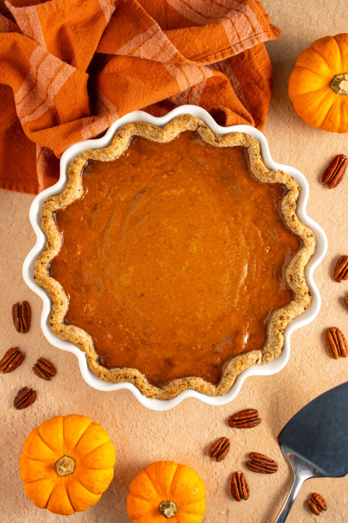 Overhead view of a white pie plate with a pumpkin pie with pecan infused crust.