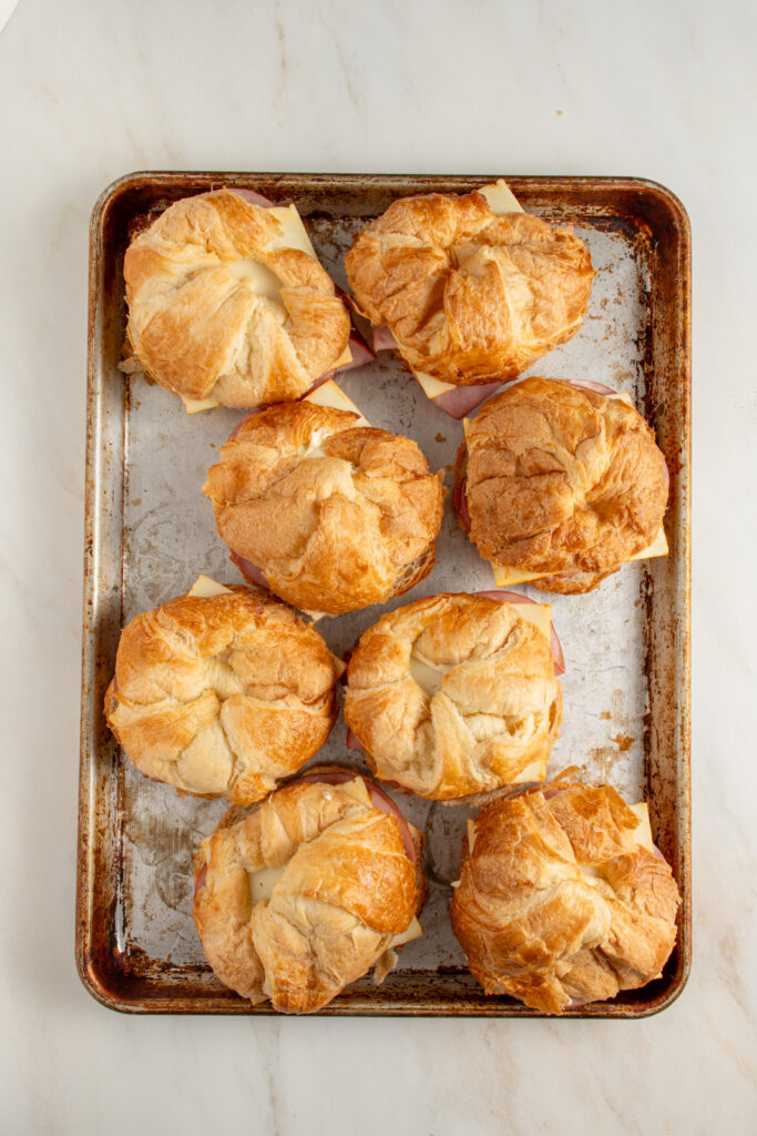 Making ham and cheese croissants on a sheet pan before they are added to the oven to bake.