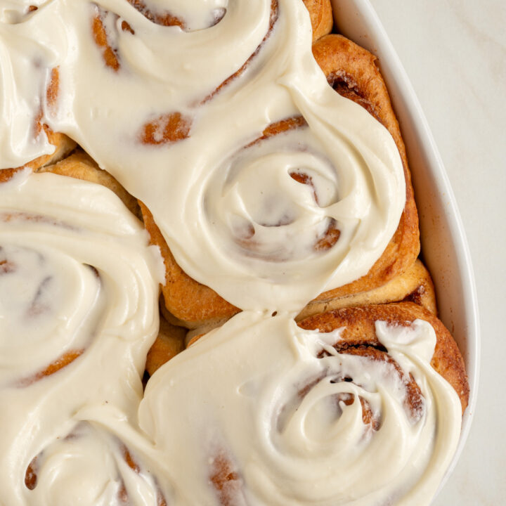 A baking dish with six small batch cinnamon rolls covered in cream cheese frosting.