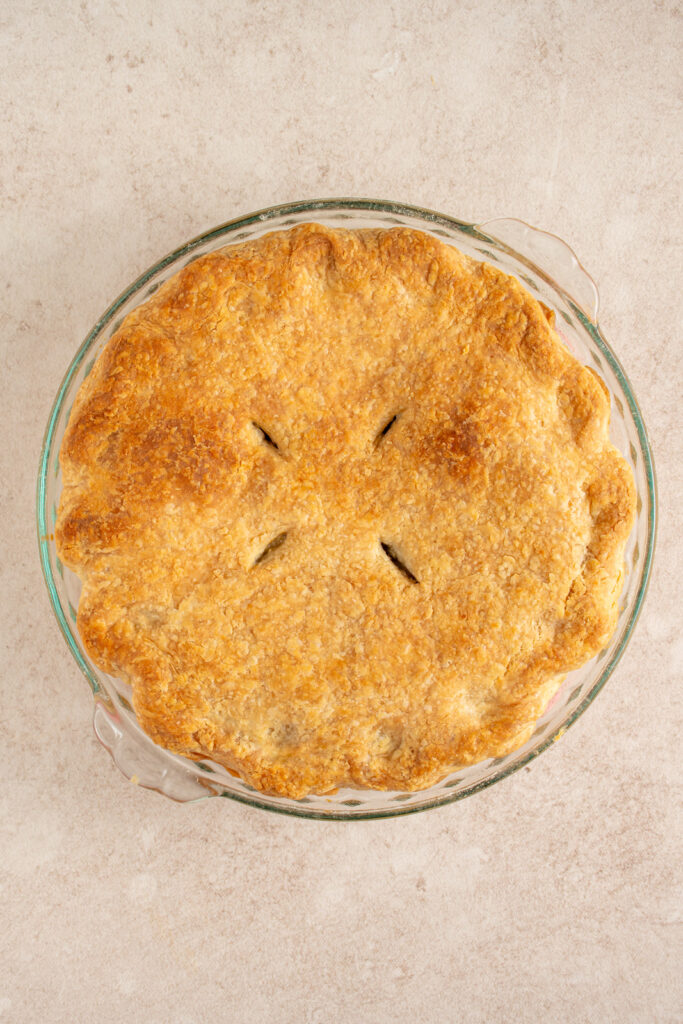 A baked Canadian pork pie on a table top with golden brown crust. 