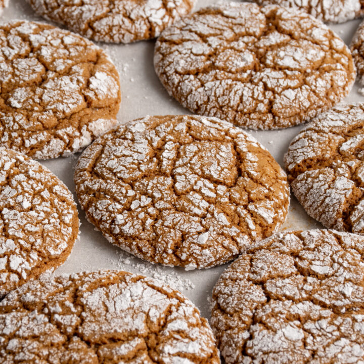 A close up of a sheet tray with freshly baked gingerbread crinkle cookies.