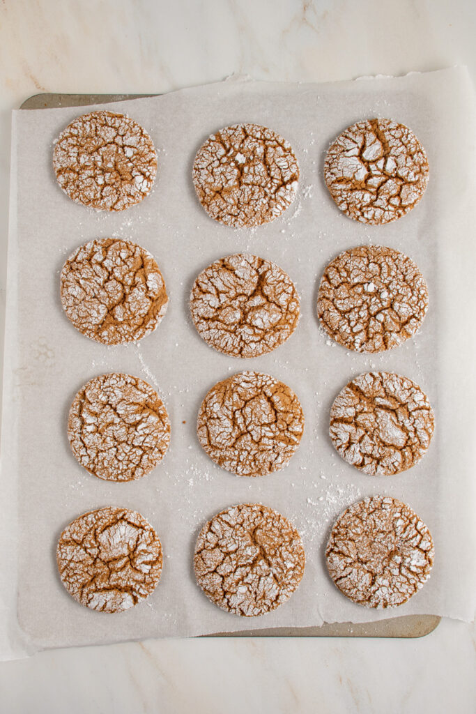 Overhead view of a cookie sheet with 12 gingerbread crinkle cookies.