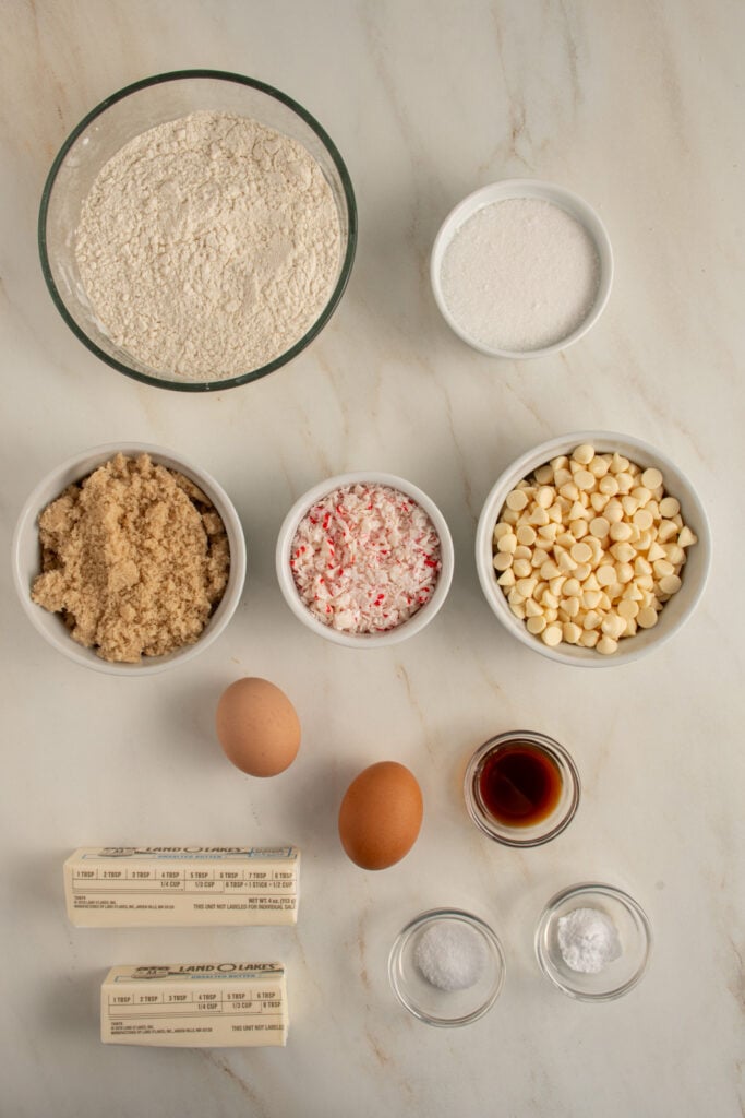 Ingredients for white chocolate candy cane cookies laid out on a tabletop.