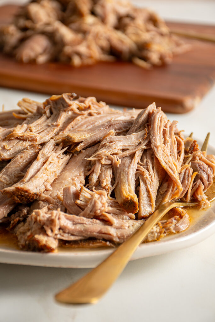 A plate with pulled pork piled high with a serving spoon.