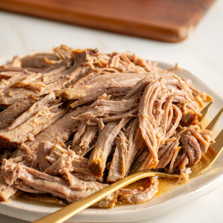 A plate filled with pulled pork and a serving spoon.