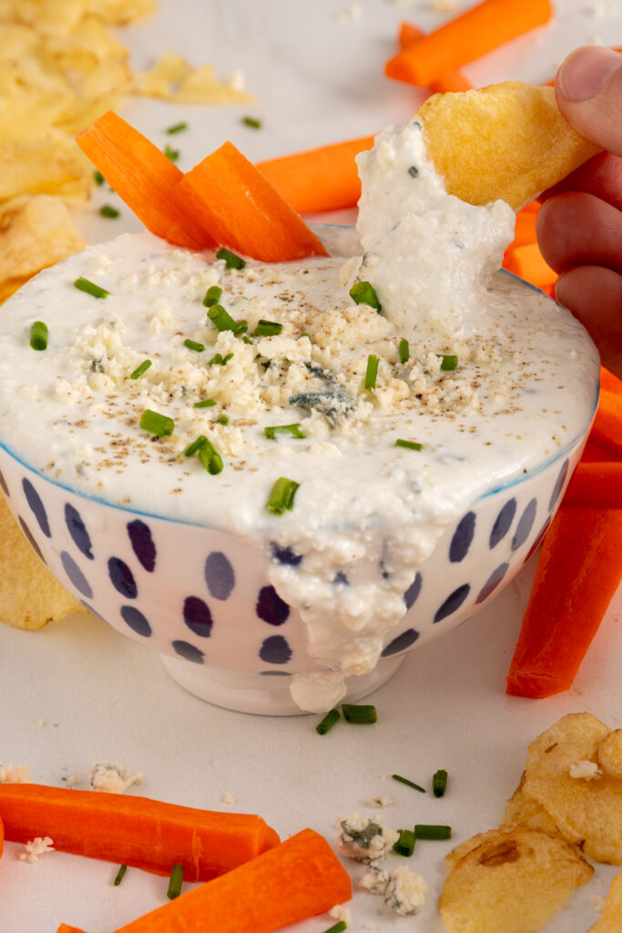 A bowl with Blue Cheese Dip garnished with blue cheese.
