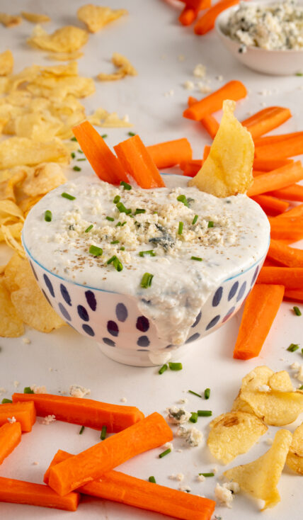 A bowl with Blue Cheese Dip garnished with blue cheese.