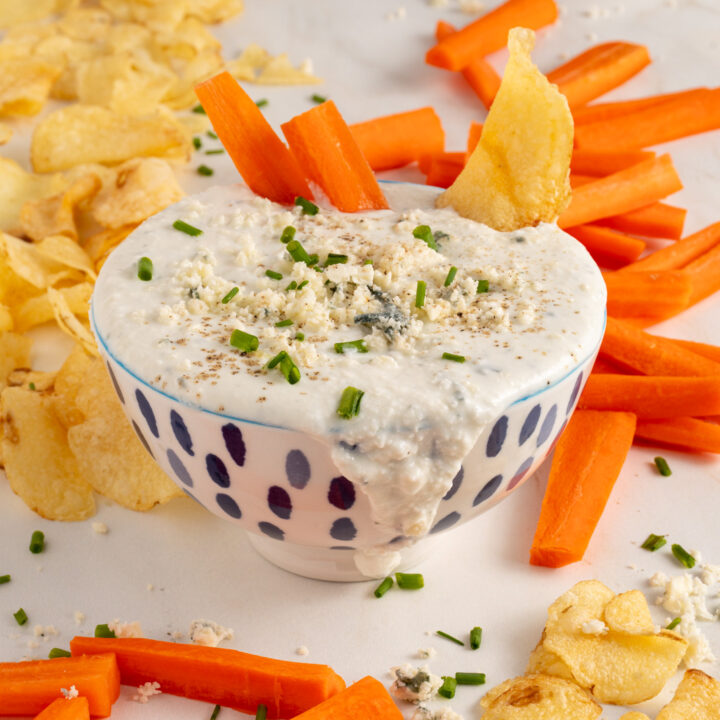 A bowl with Blue Cheese Dip garnished with blue cheese.