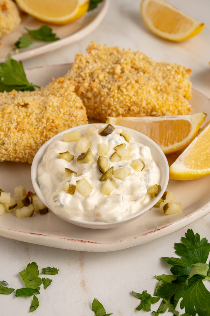A small bowl with tartar sauce made with greek yogurt garnished with chopped pickles.