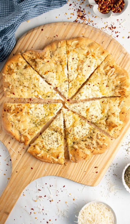 A sliced white pizza on a wood pizza peel.
