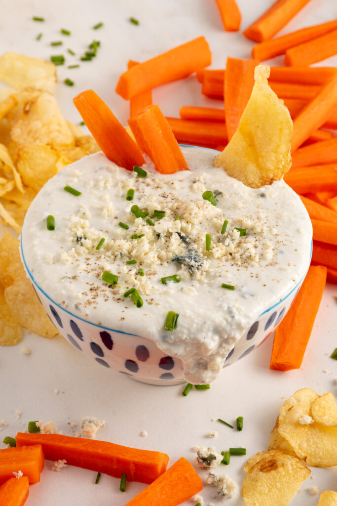 A bowl with Blue Cheese Dip garnished with blue cheese.